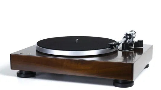 Walnut-finish hi-fi turntable with a precision tonearm in a warm listening room